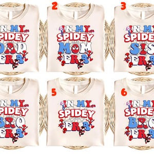 May include: Cream-colored t-shirts with the text "IN MY SPIDEY DAD ERA", "IN MY SPIDEY MOM ERA", "IN MY SPIDEY SIS ERA", "IN MY SPIDEY BRO ERA", and "IN MY SPIDEY ERA" in red, white, and blue. Each shirt features a Spider-Man graphic.