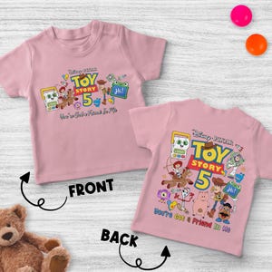 May include: Pink short-sleeved t-shirt featuring a colorful graphic of Toy Story characters and the text "Toy Story 5". The phrase "You've Got a Friend in Me" is also included. The shirt is designed for children.