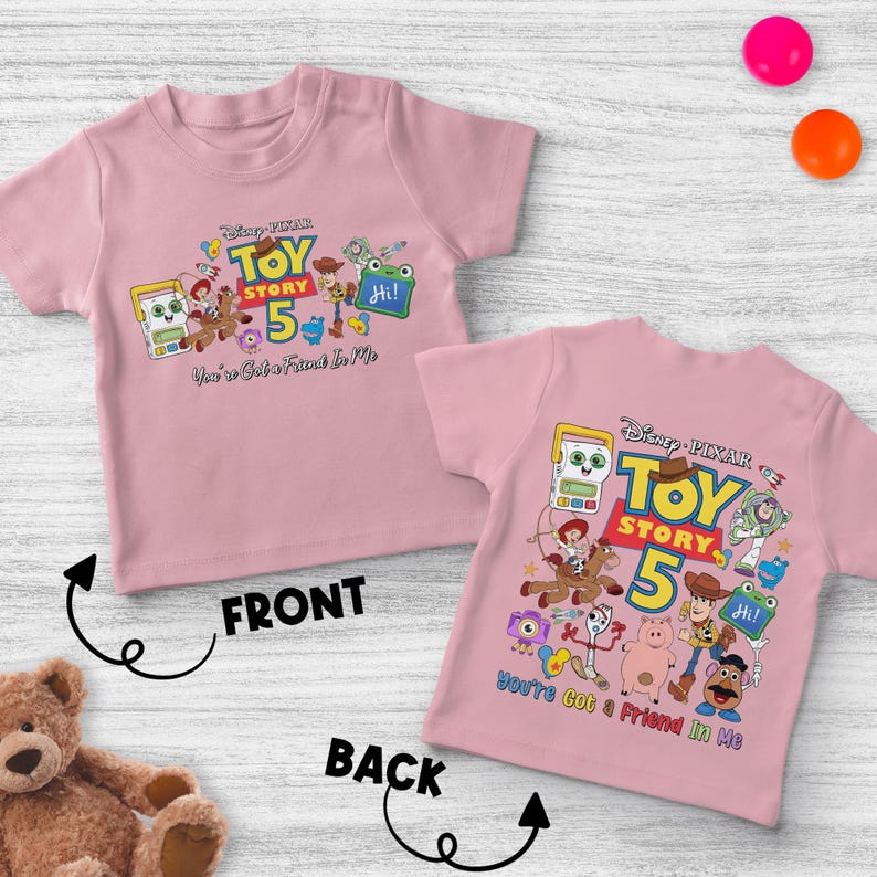 May include: Pink short-sleeved t-shirt featuring a colorful graphic of Toy Story characters and the text "Toy Story 5". The phrase "You've Got a Friend in Me" is also included. The shirt is designed for children.