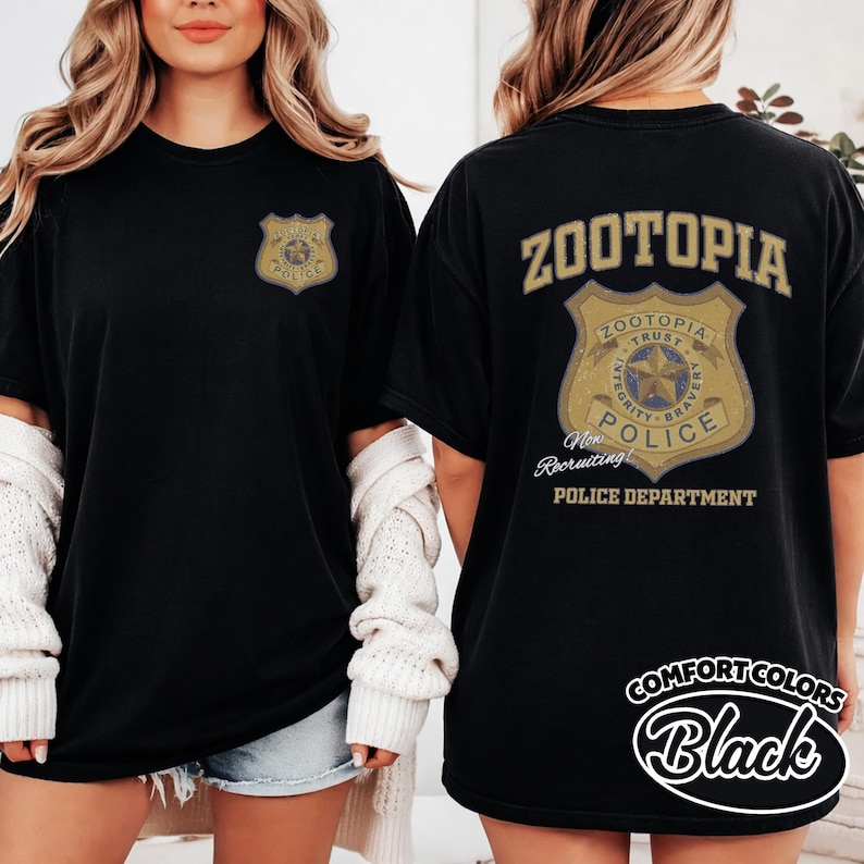 Puede incluir: Camiseta negra con un dise&ntilde;o de placa de polic&iacute;a dorada. La parte delantera de la camiseta tiene "Zootopia Police" y la trasera "Zootopia Police Department" y "New Recruiting!" en letras doradas.