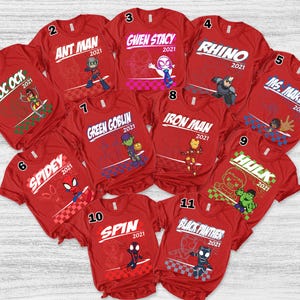May include: A collection of eleven red t-shirts featuring various Marvel characters. Each shirt has a character name and the year 2021 printed in white. Characters include Doc Ock, Ant Man, Gwen Stacy, Rhino, Ms. Marvel, Spidey, Green Goblin, Iron Man, Hulk, Spin, and Black Panther.