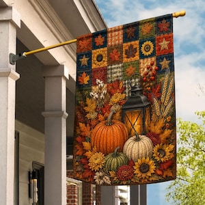 May include: A rectangular garden flag featuring a patchwork design of autumn leaves, sunflowers, and stars. The lower section displays a black lantern, orange, white, and green pumpkins, wheat stalks, cotton bolls, and vibrant fall flowers.