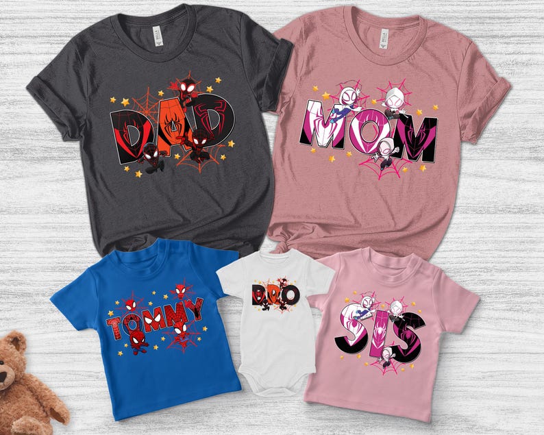 Puede incluir: Una colecci&oacute;n de camisetas y un body con dise&ntilde;os de superh&eacute;roes. Las camisetas son de varios colores, incluyendo gris, rosa y azul, con las palabras "DAD", "MOM", "TOMMY", "BRO" y "SIS" en letras negritas. Cada dise&ntilde;o incluye personajes de superh&eacute;roes y telara&ntilde;as.