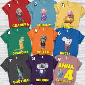 May include: A collection of colorful t-shirts featuring characters from the animated movie "Sing." Each shirt has a different character and a family-related title like "Grandpa," "Mommy," "Daddy," "Grandma," "Sister," "Uncle," "Brother," "Cousin," and "Birthday Girl."