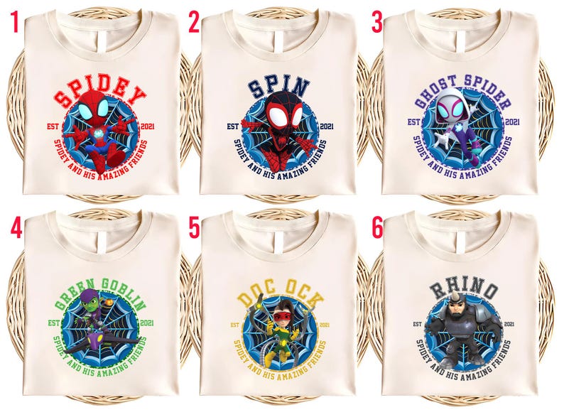 Puede incluir: Seis camisetas color crema con diferentes dise&ntilde;os de superh&eacute;roes. Cada camiseta presenta el nombre de un personaje en un c&iacute;rculo con un dise&ntilde;o de telara&ntilde;a y el texto "Spidey and His Amazing Friends". Los personajes incluyen Spidey, Spin, Ghost Spider, Green Goblin, Doc Ock y Rhino.