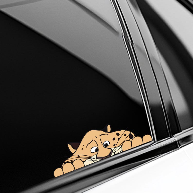 May include: A tan and brown cartoon cheetah peeking out from behind a black surface. The cheetah has black spots, a white muzzle, and a smiling expression. The image is likely a car decal.