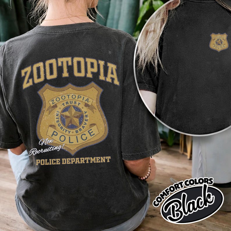 Puede incluir: Camiseta negra con la palabra "Zootopia" encima de una insignia de polic&iacute;a. La insignia incluye las palabras "Trust, Integrity, Bravery" y "Police". Tambi&eacute;n se ve el texto "Now Recruiting!" y "Police Department".