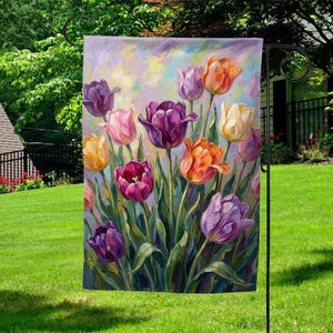 May include: A garden flag featuring a vibrant painting of tulips. The artwork showcases a variety of colors, including purple, orange, pink, and yellow, with green stems and leaves. The flag is displayed outdoors on a black metal stand.