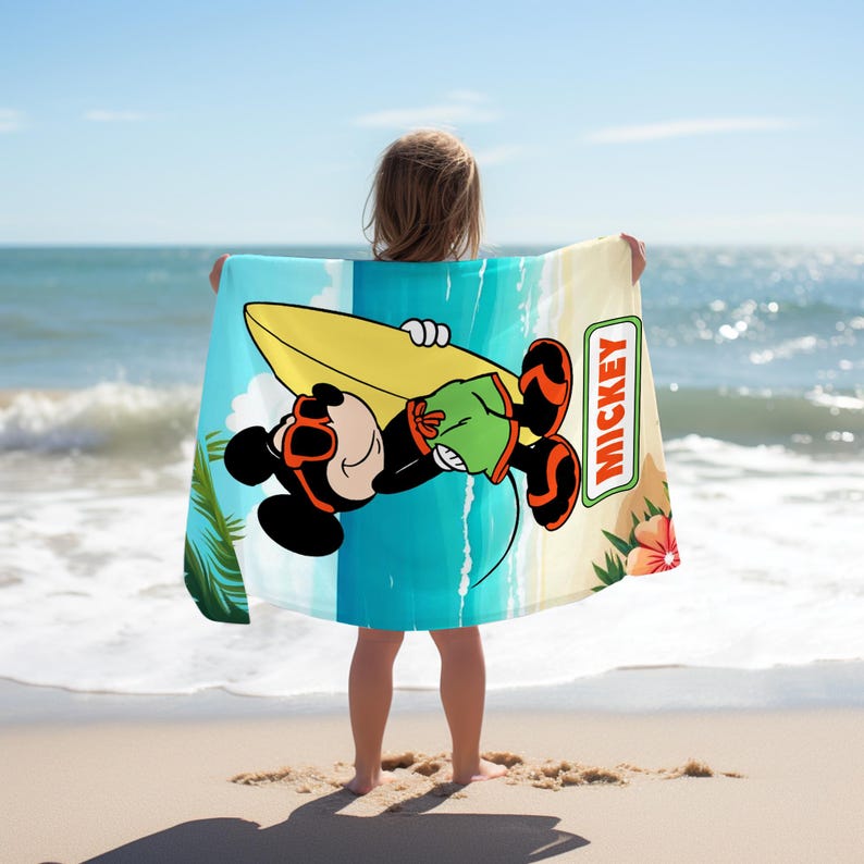 May include: A rectangular beach towel featuring a graphic of Mickey Mouse wearing sunglasses and green shorts while holding a yellow surfboard. The design includes a tropical beach background with palm leaves, a hibiscus flower, and the text MICKEY.