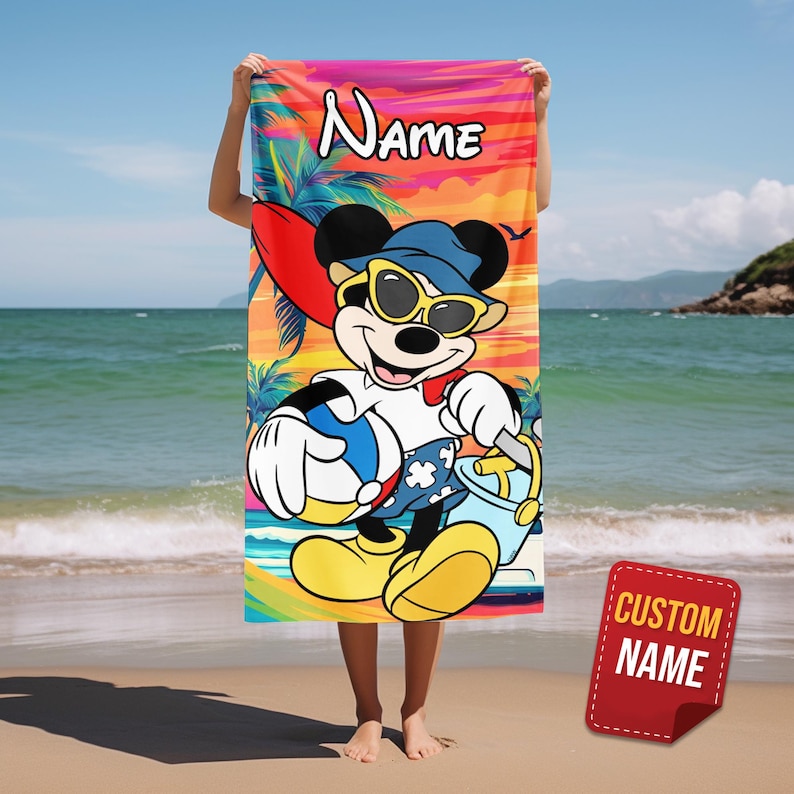 May include: A rectangular beach towel featuring a colorful sunset background with palm trees and a graphic of Mickey Mouse wearing sunglasses and a blue hat, holding a beach ball and a bucket. The word Name is printed at the top in white text.