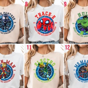 Puede incluir: Una colecci&oacute;n de camisetas con varios personajes de Marvel. Cada camiseta muestra el nombre de un personaje en un dise&ntilde;o circular con una telara&ntilde;a y el texto "Spidey and His Amazing Friends". Los personajes incluyen Black Panther, Trace-E, Hulk, Iron Man, Electro y Ms. Marvel.