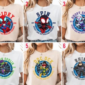 Puede incluir: Seis camisetas con personajes de Spider-Man. Cada camiseta muestra el nombre de un personaje, como "Spidey" o "Rhino", dentro de un dise&ntilde;o de telara&ntilde;a, junto con el texto "Spidey and His Amazing Friends" y el a&ntilde;o "2021".