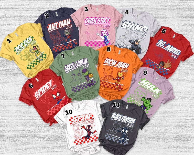 May include: A collection of eleven colorful t-shirts featuring various Marvel characters. Each shirt displays a character's name and the year 2021, along with a corresponding graphic design. The shirts are arranged in a circular pattern.