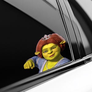 May include: A sticker featuring Princess Fiona from the animated movie Shrek, peeking out of a car window. She has green skin, red hair, and a silver crown. She is wearing a blue dress and a necklace.