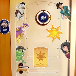 May include: A cream-colored door decorated with cartoon stickers of characters and symbols from the movie Tangled. The door has a circular window with the number 5192, a sun, and a lantern.