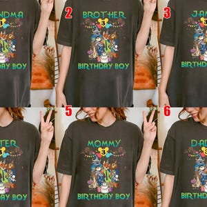 May include: A dark gray t-shirt featuring a graphic of various cartoon characters, a birthday cake, and colorful bunting. The text includes the number 3 inside a yellow circle, and the words BIRTHDAY BOY, along with custom labels like GRANDMA, BROTHER, JAMES, SISTER, MOMMY, or DADDY.