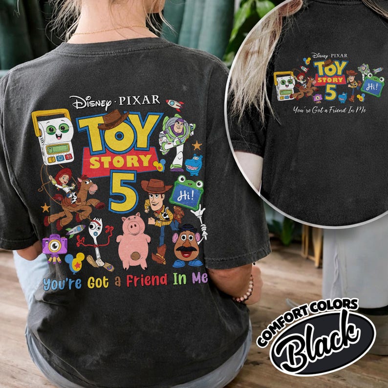 May include: Black t-shirt featuring a colorful graphic of Toy Story characters and the text "Toy Story 5". The design includes Woody, Buzz Lightyear, and other characters from the movie. The phrase "You're Got a Friend In Me" is also included.