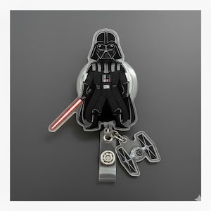 May include: A Star Wars-themed badge reel featuring Darth Vader with a red lightsaber and a TIE fighter. The badge reel is black, white, and gray, with a clear plastic overlay. The reel has a retractable cord and a belt clip.