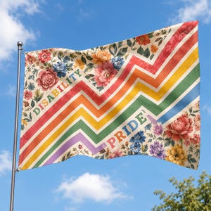 May include: A rectangular flag featuring a floral pattern on the top left and bottom right corners. The center displays diagonal zigzag stripes in red, orange, yellow, green, blue, and purple. The text DISABILITY PRIDE is printed on the stripes.