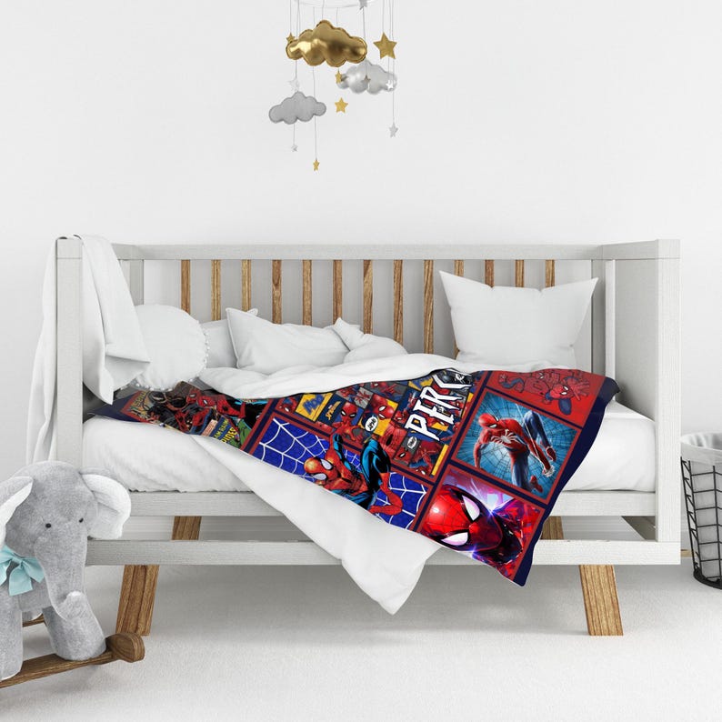 May include: A Spider-Man themed baby blanket with a colorful design. The blanket features various action poses of Spider-Man in a grid pattern against a blue and red background. The blanket is draped over a white crib.
