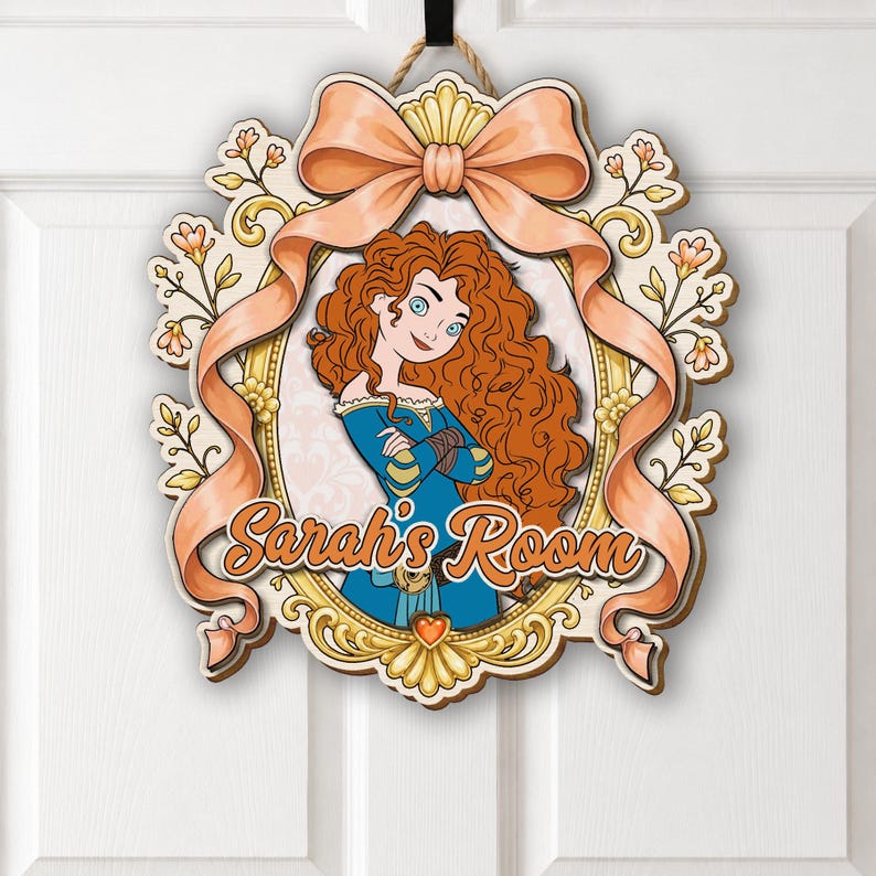 May include: A decorative wooden door sign featuring a cartoon illustration of a character with long curly red hair in a blue dress, framed by a gold border and a peach-colored ribbon. The text Sarah's Room is printed in orange script.