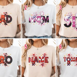 Puede incluir: Una colecci&oacute;n de camisetas con dise&ntilde;os tem&aacute;ticos de superh&eacute;roes. Cada camiseta muestra una palabra diferente: DAD, MOM, SIS, BRO, NAME y TOMMY. Los dise&ntilde;os incorporan telara&ntilde;as, estrellas y personajes de superh&eacute;roes en varios colores.