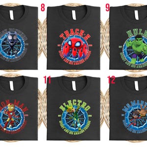 Puede incluir: Camisetas negras con dise&ntilde;os de superh&eacute;roes. Cada camiseta muestra un personaje diferente, incluyendo Black Panther, Trace-E, Hulk, Iron Man, Electro y Ms. Marvel, con sus nombres e im&aacute;genes relacionadas. Los dise&ntilde;os est&aacute;n dentro de un gr&aacute;fico de telara&ntilde;a.