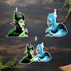 Puede incluir: Juego de tres pegatinas con ilustraciones de dibujos animados de Mal&eacute;fica y Hades. Las pegatinas muestran a los personajes en varias poses, con colores vibrantes y contornos audaces. Sobre un fondo de madera oscura.