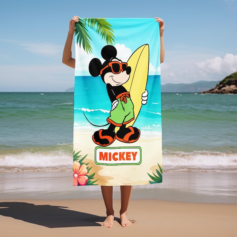 May include: A rectangular beach towel featuring a graphic of Mickey Mouse wearing orange sunglasses and green swim trunks while holding a yellow surfboard. The design includes palm leaves, a hibiscus flower, and the text MICKEY in a green box.