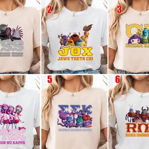 May include: A collection of six t-shirts, each featuring a different design with cartoon characters and text. The shirts are in various colors, including white and beige. The text includes phrases like "HSS ETA HISS HISS", "JOX JAWS THETA CHI", and "PNK PYTHON NU KAPPA".