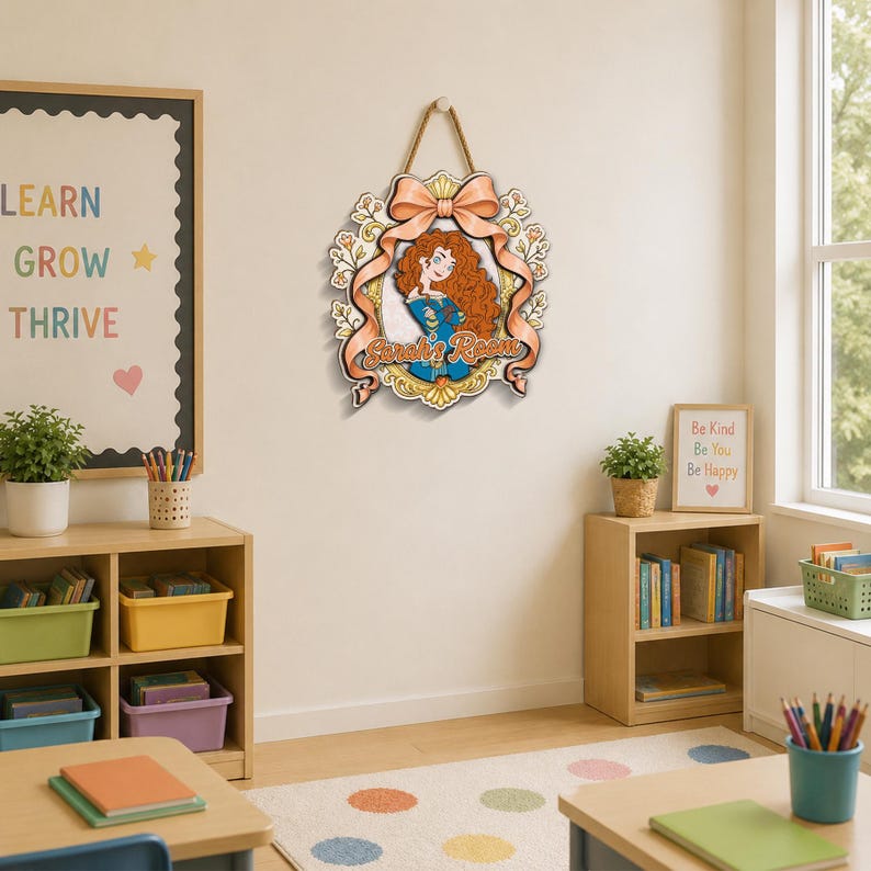 May include: A decorative wooden wall sign featuring a cartoon character with long curly red hair in a blue dress, framed by a peach-colored ribbon and floral accents. The text "Sarah's Room" is printed in a script font across the center.