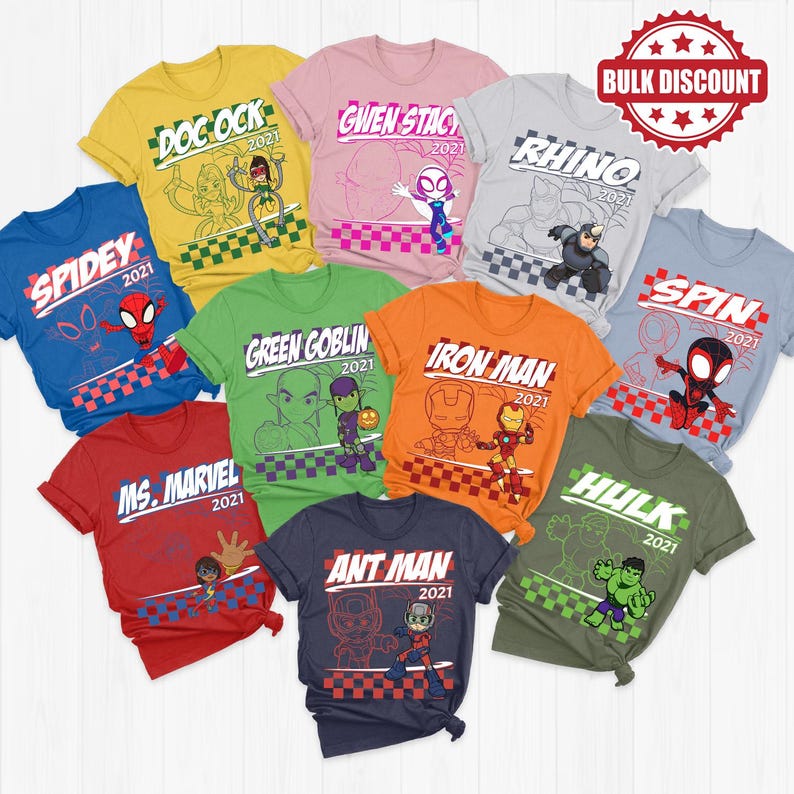 May include: A collection of colorful t-shirts featuring various superhero characters. Each shirt displays a character's name and the year 2021, with vibrant graphics and designs. The shirts are in various colors, including blue, red, green, and orange.