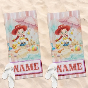 May include: Two rectangular beach towels featuring a cartoon cowgirl character with red hair, a yellow shirt, and a red hat under a pink umbrella. The design includes a sandcastle, beach ball, and seashells, with a white box containing the text NAME.