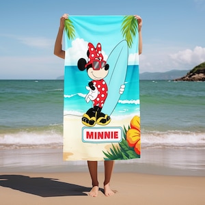 May include: A rectangular beach towel featuring a graphic of Minnie Mouse wearing red polka-dot swimwear, a matching bow, and sunglasses while holding a light blue surfboard. The design includes palm leaves, a hibiscus flower, and the name MINNIE.