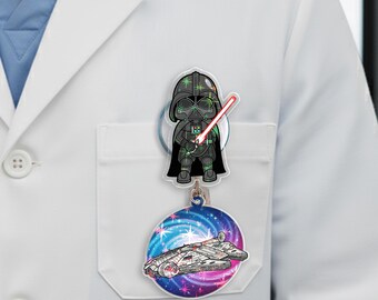 May include: A retractable badge reel featuring a cartoon Darth Vader with a red lightsaber and a Millennium Falcon design. The reel has a clear plastic covering and a metal clip for attaching to clothing.
