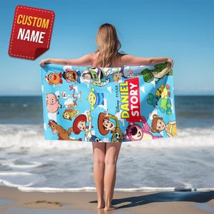 May include: A light blue beach towel featuring a colorful print of various Toy Story characters, including Woody, Buzz Lightyear, and Jessie, with the text DANIEL STORY prominently displayed in a red and yellow vertical graphic design.