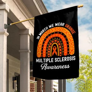 May include: Black flag with the text "IN MARCH WE WEAR ORANGE" and "MULTIPLE SCLEROSIS Awareness". The flag features a rainbow design with orange and yellow accents and a ribbon symbol.