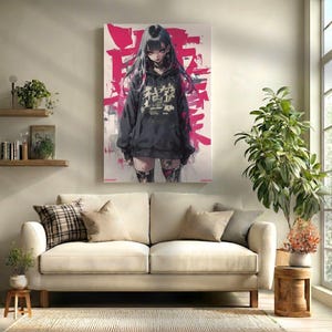 Op de afbeelding: Een canvas print met een digitale illustratie van een persoon met lang zwart haar in een zwarte hoodie met Japanse tekst. De achtergrond heeft roze penseelstreken. Het kunstwerk hangt boven een cr&egrave;mekleurige bank.