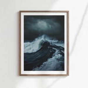Op de afbeelding: Een ingelijste print met een dramatische oceaangolf. De afbeelding toont een donkere, stormachtige zee met een grote golf die breekt. De golf is een mix van donkerblauw en wit, wat een opvallend contrast creëert.