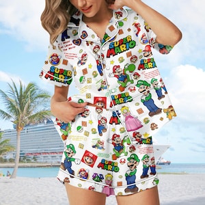 May include: White pajama set featuring Super Mario characters. The short-sleeved top and shorts are covered in images of Mario, Luigi, Princess Peach, and other characters. The words "Super Mario" are printed on the set.