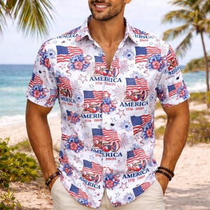 May include: White short-sleeve shirt with a patriotic print. The design features American flags, fireworks, and floral accents in red, white, and blue. The text "AMERICA 1776-20125" is also printed on the shirt.