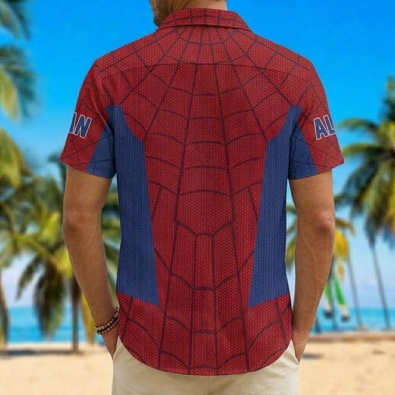 K&ouml;nnte beinhalten: Rotes und blaues kurz&auml;rmeliges Hemd mit Spinnennetz-Design. Das Hemd hat blaue Seitenteile und die Buchstaben "IN" und "AL" auf den &Auml;rmeln. Das Hemd wird von einer Person getragen.