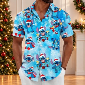 May include: A short-sleeved button-down shirt in light blue featuring an all-over print of the character Stitch from Lilo and Stitch. The character is depicted wearing a red Santa hat and scarf, tangled in colorful Christmas lights.