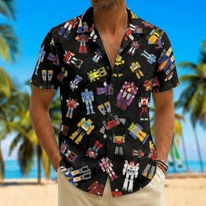 May include: A black short-sleeve button-down shirt featuring an all-over print of colorful robot figures in various poses. The shirt has a classic collar, a front button placket, and a straight hem, showcasing a repeating pattern of mechanical characters.