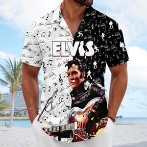 Può includere: Una camicia a maniche corte con bottoni e design diviso. Il lato sinistro è bianco con note musicali nere e firme di Elvis Presley. Il lato destro è nero con sagome e firme bianche. Al centro, Elvis è raffigurato mentre suona la chitarra.