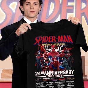 May include: A black t-shirt featuring a graphic of multiple Spider-Man characters, the text "SPIDER-MAN BRAND NEW DAY 24TH ANNIVERSARY 2002-2026", a list of movie titles, actor names with their signatures, and the phrase "THANK YOU FOR THE MEMORIES".