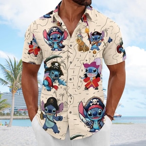 May include: A short-sleeved button-down shirt in a light beige color featuring an all-over print of the blue character Stitch dressed as a pirate. The pattern includes illustrations of Stitch with swords, hats, and cannons against a map background.