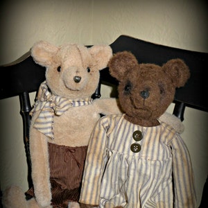May include: Two handmade plush teddy bears sitting on a black wooden chair. The bear on the left is tan with a striped scarf and brown corduroy pants. The bear on the right is brown with a striped dress and two brown buttons.
