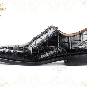 Handmade men’s black crocodile-style textured leather lace-up dress shoes with a polished finish. Crafted with genuine leather upper, cushioned insole, leather lining, and durable outsole for all-day comfort and support. Designed for weddings, parties, office wear, and formal business occasions. A premium handmade shoe that blends luxury, craftsmanship, and timeless sophistication for modern gentlemen. mens formal shoes
wedding shoes men
party wear shoes
business shoes men
polished dress shoes