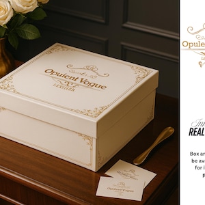 May include: A cream-colored box with gold decorative accents and the text "Opulent Vogue Leather." The box sits on a dark wooden surface with a gold-colored spoon and two cards. A vase of white roses is in the background.